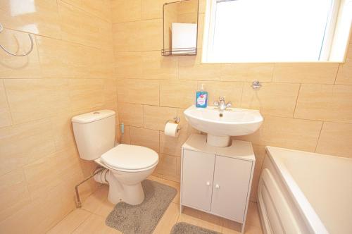 y baño con aseo, lavabo y bañera. en Cosy family home w/Wi-Fi, parking, self check-in en Londres