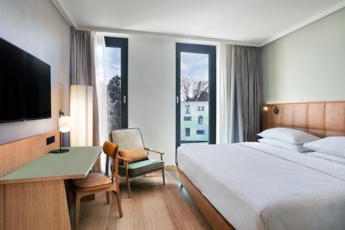 a bedroom with a bed and a desk and a television at Four Points by Sheraton Ljubljana Mons in Ljubljana