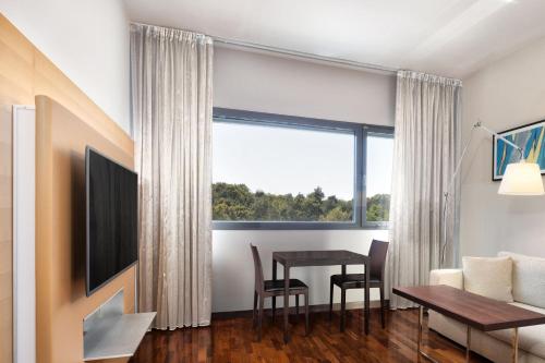 a living room with a dining room table and a large window at Four Points by Sheraton Ljubljana Mons in Ljubljana