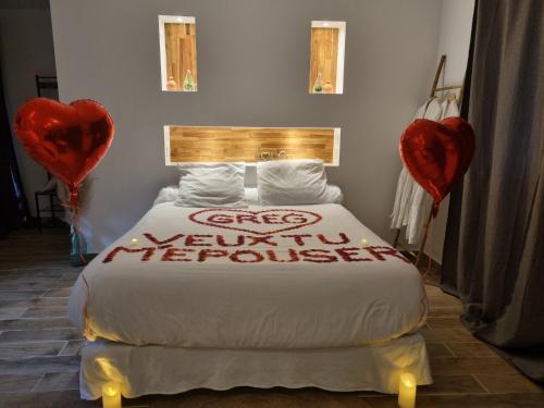 a bedroom with a bed with two red heart balloons at Suite de charme avec JACUZZI illimité et jardin privatif in Saint-Prix