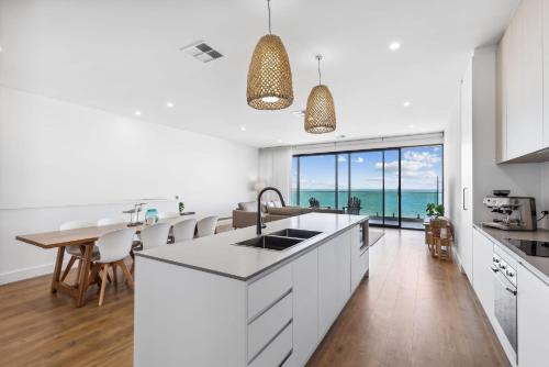 a kitchen with white cabinets and a view of the ocean at Seamist On Seagull WiFi in Hayborough