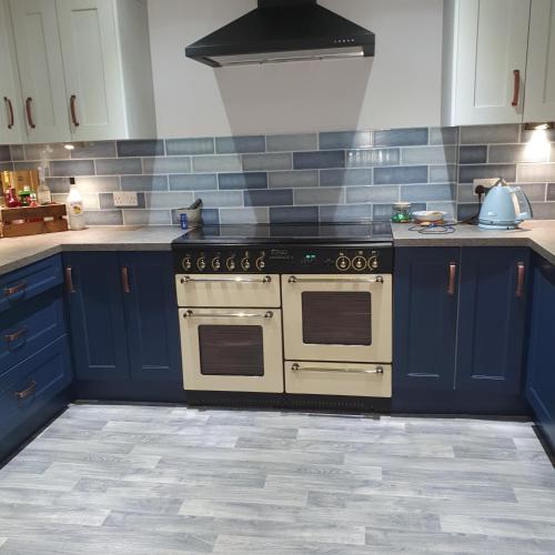 a kitchen with a stove and blue cabinets at Ellesmere port in Sutton
