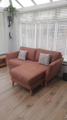 um sofá castanho numa sala de estar com janelas em Ellesmere port em Sutton