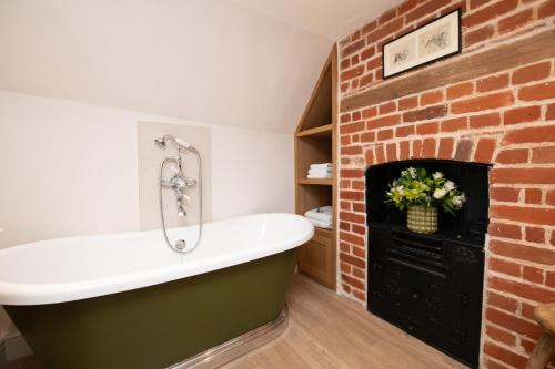 a bathroom with a brick fireplace and a bath tub at The Lion in East Bergholt