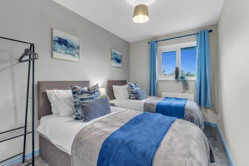 two beds in a room with blue curtains at MK 2-Bedroom Contractor's Gem, 5 beds, sleeps 6, free parking in Milton Keynes