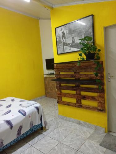 Pedro Juan CaballeroにあるEl Viajero Hostel & Suítes 11の黄色の壁にテレビとベッドが備わる黄色の部屋