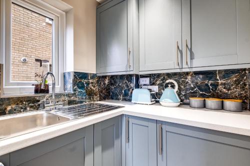 a kitchen with white cabinets and a sink at MK 2-Bedroom Contractor's Gem, 5 beds, sleeps 6, free parking in Milton Keynes