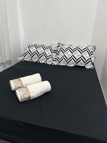 Una cama con dos toallas enrolladas encima. en Suite 1- black em Praia bonita hospedagem, en São Francisco do Sul