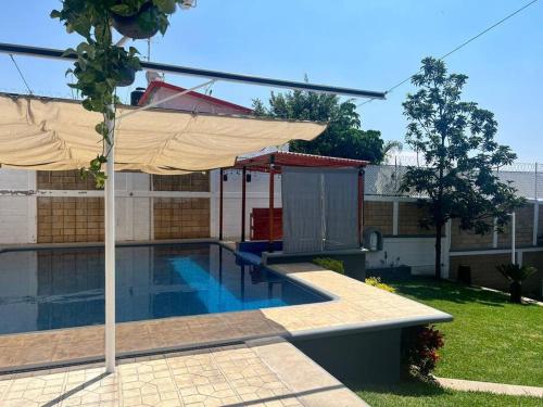 una piscina con sombrilla junto a una casa en CASA Punto Medio en Tlayacapan