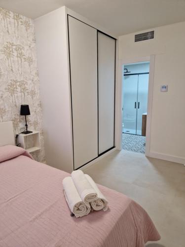 a bedroom with a pink bed with towels on it at APARTAMENTO V27 in Baeza