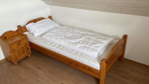 a wooden bed with white sheets and a wooden night stand at Ferienhaus Seepark Kirchheim in Kirchheim