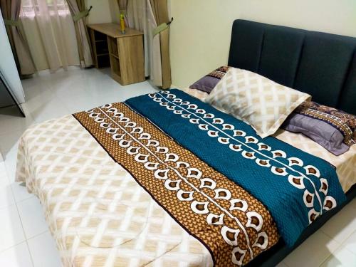a bed with a blue and white blanket on it at Sya Al-Yahya Homestay in Kuala Terengganu