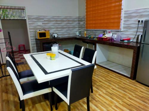 uma cozinha com uma mesa e cadeiras numa cozinha em Sya Al-Yahya Homestay em Kuala Terengganu