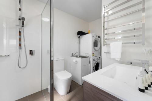 uma casa de banho branca com um WC e uma máquina de lavar roupa em T Bar on Twynam em Jindabyne