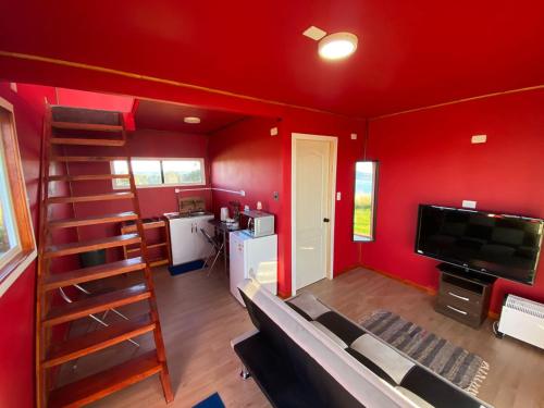 sala de estar con pared roja y escalera de caracol en Departamentos altos de yelqui, en Puqueldón