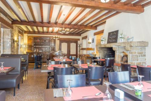 a restaurant with tables and chairs and a fireplace at Hotel Le Bourgogne in Cuiseaux