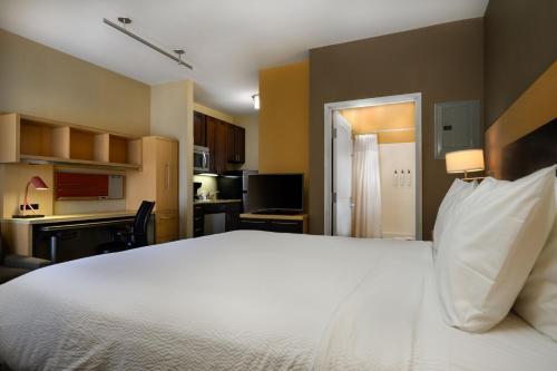 a bedroom with a large white bed and a kitchen at TownePlace Suites by Marriott Houston Westchase in Houston