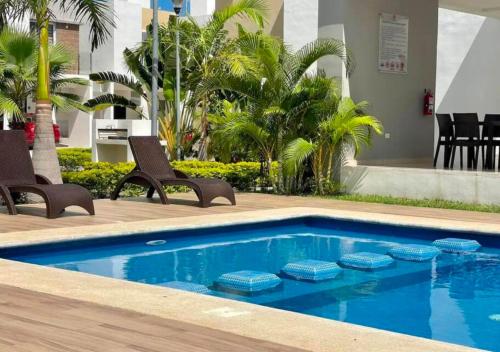 a swimming pool with two chairs and a table at Casa familiar en condominio privado cerca de playa in Cancún