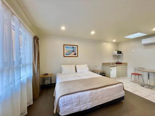 a hotel room with a large bed and a table at Hobson's Choice Motel in Dargaville