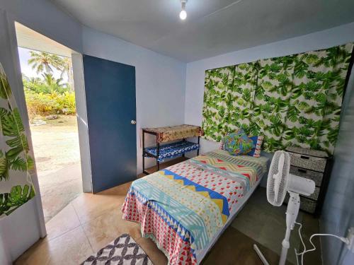 Titikawekaにある2rangi Beach Homestay at Mirimiri Spaのベッドルーム1室(ベッド1台付)と壁に葉が付いています。