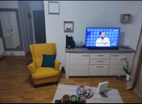 un soggiorno con TV e sedia gialla di Logement à côté de l'aéroport Orly ad Athis-Mons