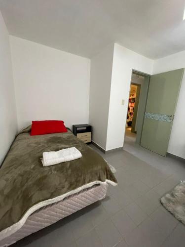 a bedroom with a large bed with a red pillow at La casita de sol in Puerto Madryn