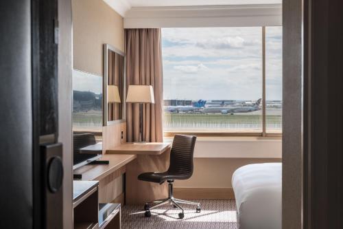 Habitación de hotel con escritorio, silla y ventana en Renaissance London Heathrow Hotel, en Hillingdon