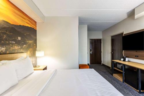 a hotel room with a bed and a flat screen tv at Clarion Pointe Sevierville-Pigeon Forge in Sevierville