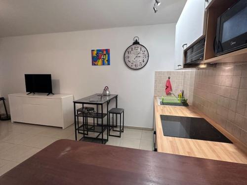 a kitchen with a counter and a clock on the wall at Studio Bellepierre in Saint-Denis