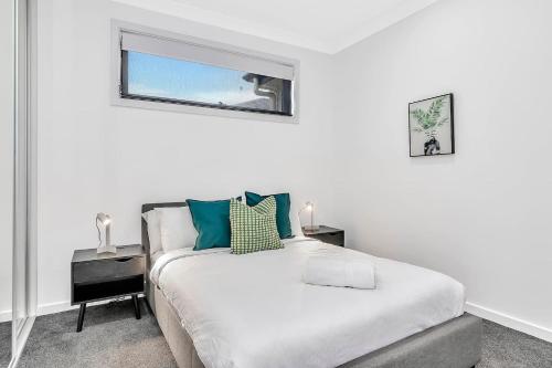 une chambre blanche avec un lit et une fenêtre dans l'établissement The Art of Zen - Modern Comfort between Beach and CBD, à Adélaïde