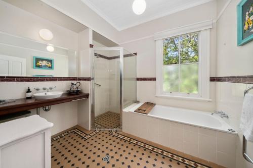 a bathroom with a tub and a sink and a window at Berdea in Leura