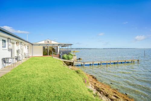 a house with a dock next to a body of water at Meningie Waterfront Motel in Meningie