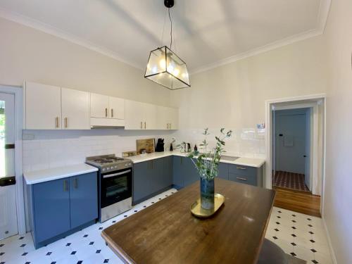 a kitchen with blue cabinets and a wooden table at Roseland Cottage - CBD Heritage in Orange