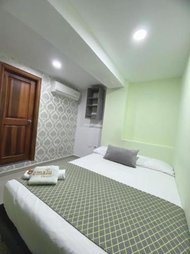 ein Schlafzimmer mit einem großen weißen Bett mit grünem Muster in der Unterkunft Hotel Emalú M&C in Quibdó