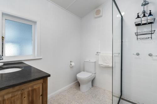 a bathroom with a toilet and a glass shower at Johnno's Cottage - Prime Location - Sleeps 4 in Orange