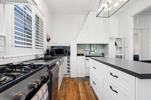 a kitchen with white cabinets and a black counter top at Johnno's Cottage - Prime Location - Sleeps 4 in Orange
