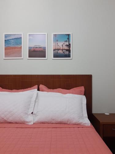 a bedroom with a bed with four pictures on the wall at Casa da Tati in Florianópolis