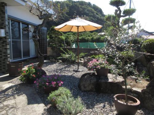 a garden with an umbrella and some plants and flowers at 一棟貸ゲストハウス　パンジー in Nachikatsuura