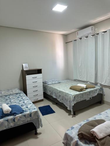 a bedroom with two beds and a dresser in it at Flat Davisis 3 - PX da JK in Palmas