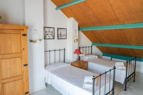 a bedroom with two beds and a wooden ceiling at Casa de lujo en la playa frente al campo de golf in El Portil