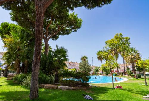 una piscina en un parque con árboles y césped en Casa de lujo en la playa frente al campo de golf, en El Portil