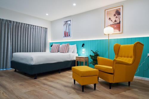 a bedroom with a bed and a yellow chair at Red Star Palm Beach in Gold Coast