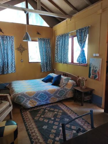 a bedroom with a bed and blue curtains at CABAÑA JACARANDA in Horcon