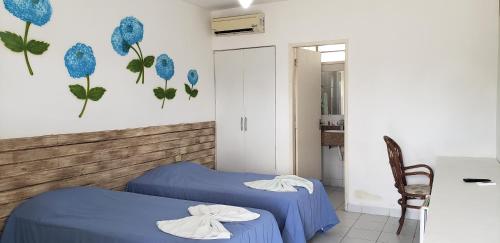 2 Betten in einem Zimmer mit blauen Blumen an der Wand in der Unterkunft Pousada Fazenda Gloria in Lagoa dos Gatos