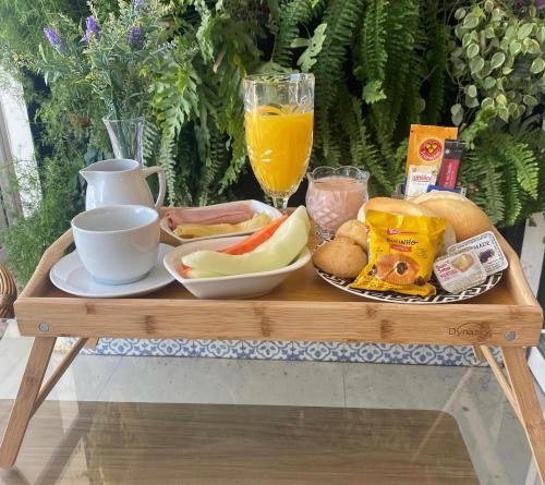 a wooden table with a tray of food and a glass of orange juice at Flats Uberlândia in Uberlândia