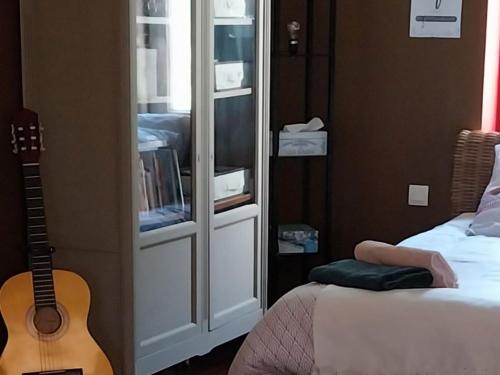 ein Schlafzimmer mit einer Gitarre neben einem Bett und einer Gitarre in der Unterkunft Gîte Courgenard, 1 pièce, 2 personnes - FR-1-410-338 in Courgenard