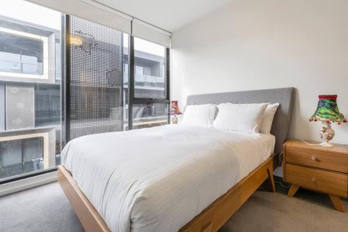 Un dormitorio con una cama grande y una ventana en City-edge Living in Trendy North Melbourne en Melbourne