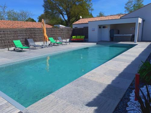 - une piscine avec des chaises et un parasol dans l'établissement Maison rénovée avec jardin, piscine chauffée et spa, proche plages vendéennes, idéal pour familles - FR-1-426-481, à La Garnache