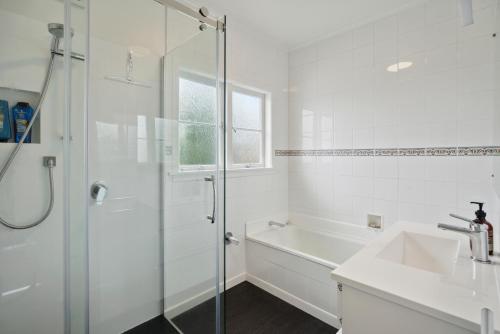 een witte badkamer met een douche en een wastafel bij Sun-drenched Bach - Leigh Holiday Home in Leigh