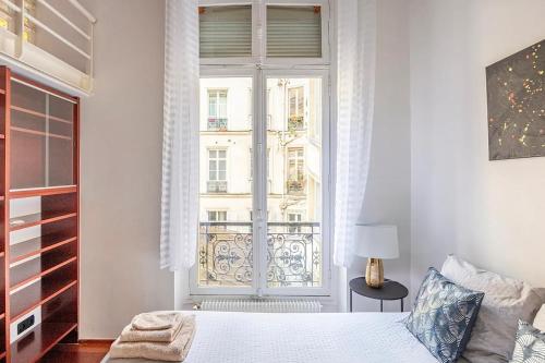 a bedroom with a bed and a large window at Chic Parisian Flat in Paris